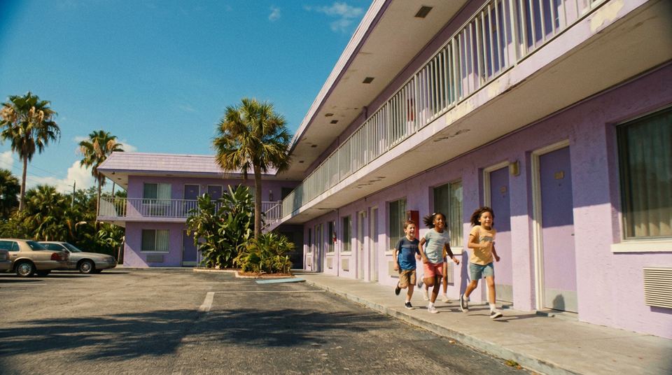 Children running past a lilac motel under palm trees