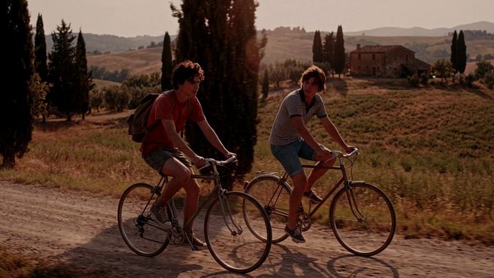 The same shot of two cyclists, graded by AI Color Match to the Red Lantern Courtyard look